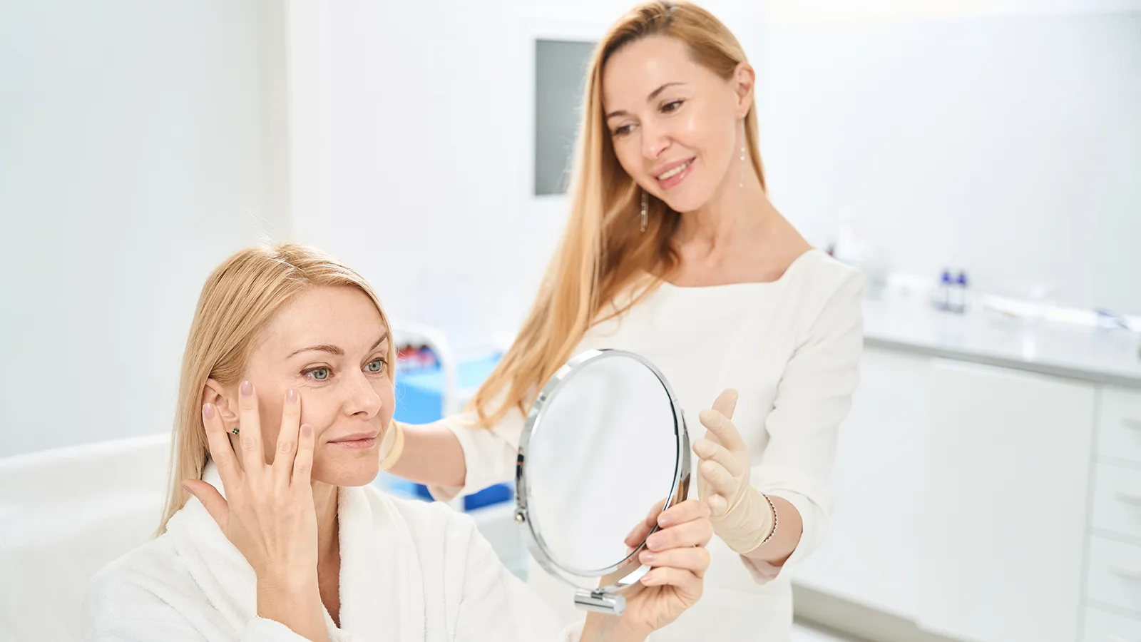 woman receiving medical aesthetics treatments, looking in mirror