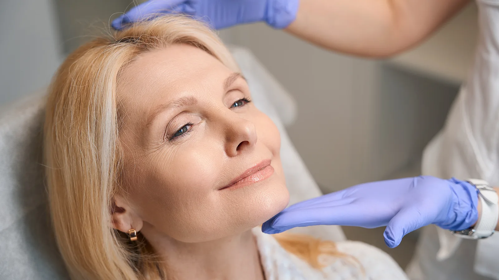woman receiving medical aesthetics treatments with gloves hands framing her face